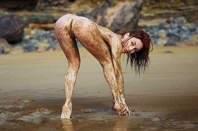Gorgeous redhead gets dirty by covering her sexy body in mud outdoors