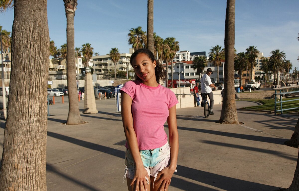 Ebony beauty lifts her shirt on the pier to show off her small breasts