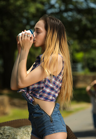 A girl in denim clothes Melody Rose drinking morning coffee in her backyard
