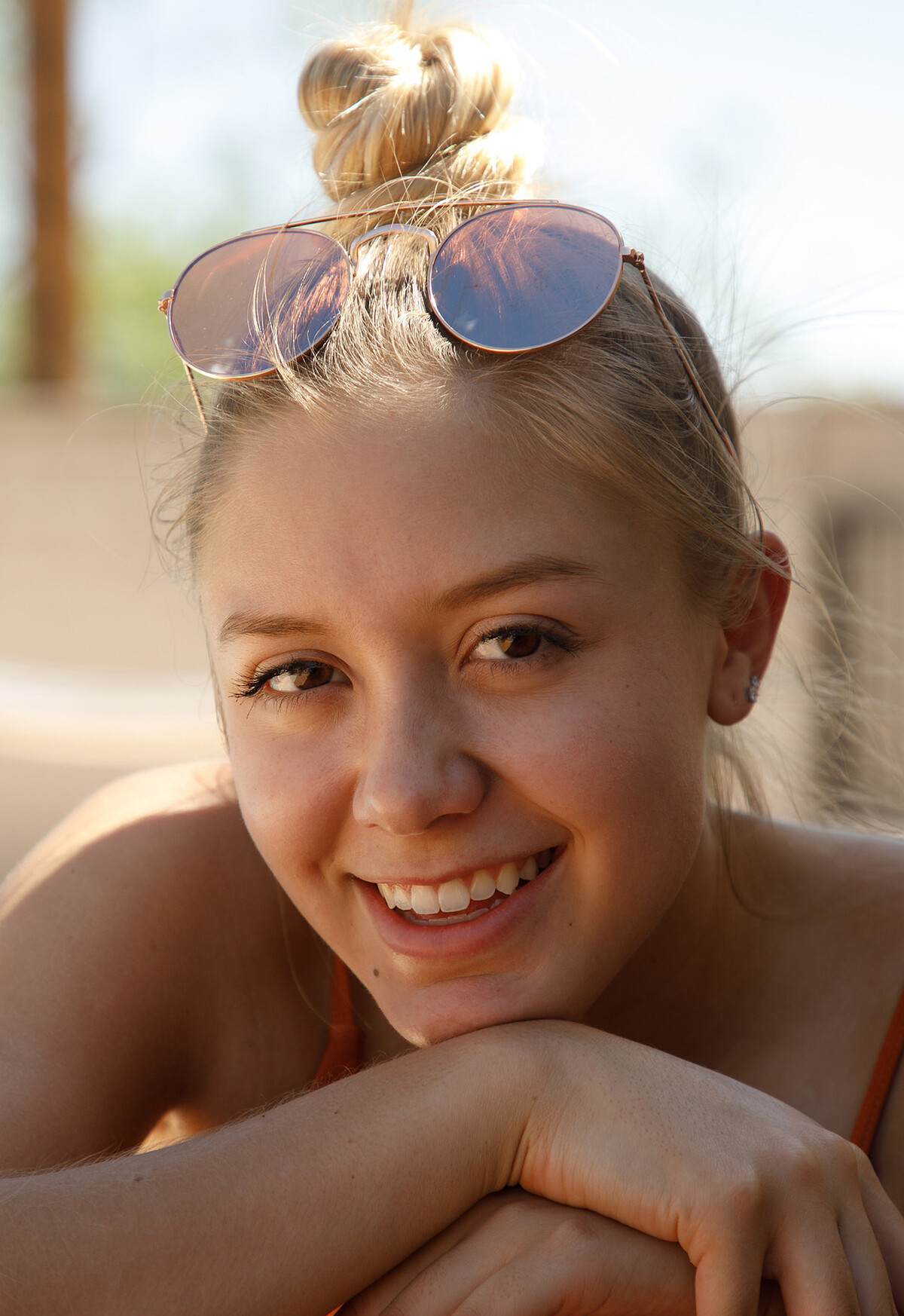 A girl with beautiful smile enjoys a hot sunny day in topless poolside