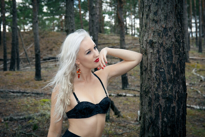 Blonde vixen Adelina White baring her tits and pussy while posing in the woods