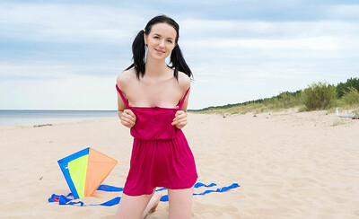 Skinny angel undresses her cute summer outfit to show her figure while posing on the sandy beach