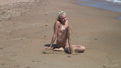 Cute and playful blondie sensually plays naked on the sand