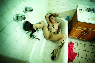 Adventurous hottie flaunting her nude and soaking wet body full of tattoos as she poses in a bathtub