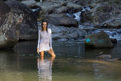 A hot babe drops her transculent rain suit, revealing her amazing bod out in nature's rawness, making that rocky river scenic as hell with her nakedness.
