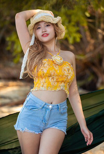 Her golden blonde hair spills from beneath the wide-brimmed straw hat.