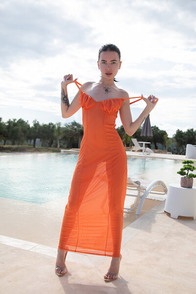 Lyleen's wet, pale skin glistens as her soaked orange dress clings tightly to her sexy body by the pool.