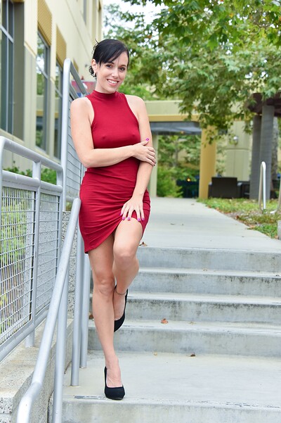 She flashes her bare pussy against a tree, fingering herself in that tight red dress before leaving.