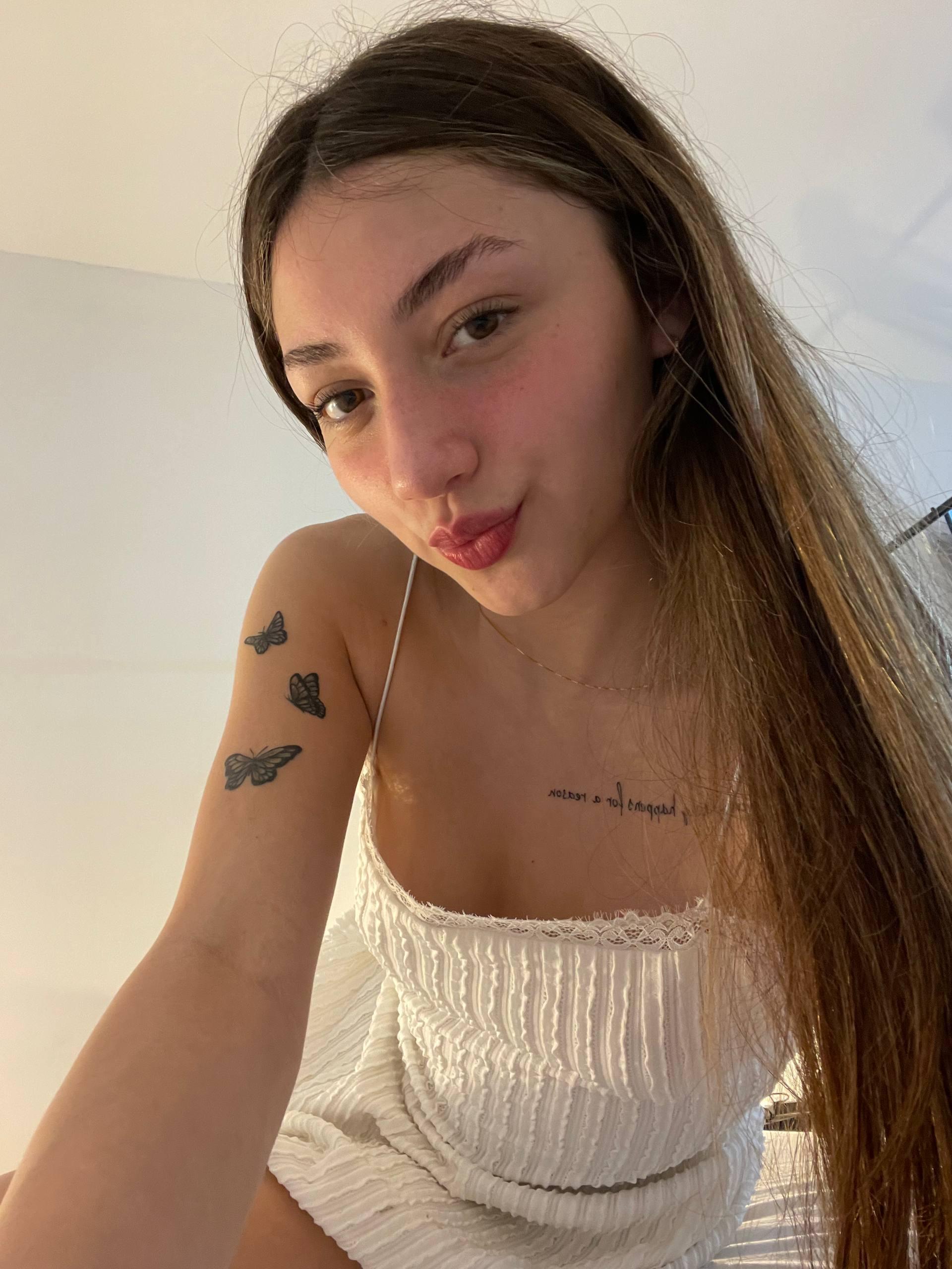 Kiera Brooks's tongue teasingly touches her lips, her white dress barely covering her eager, tattooed breasts.