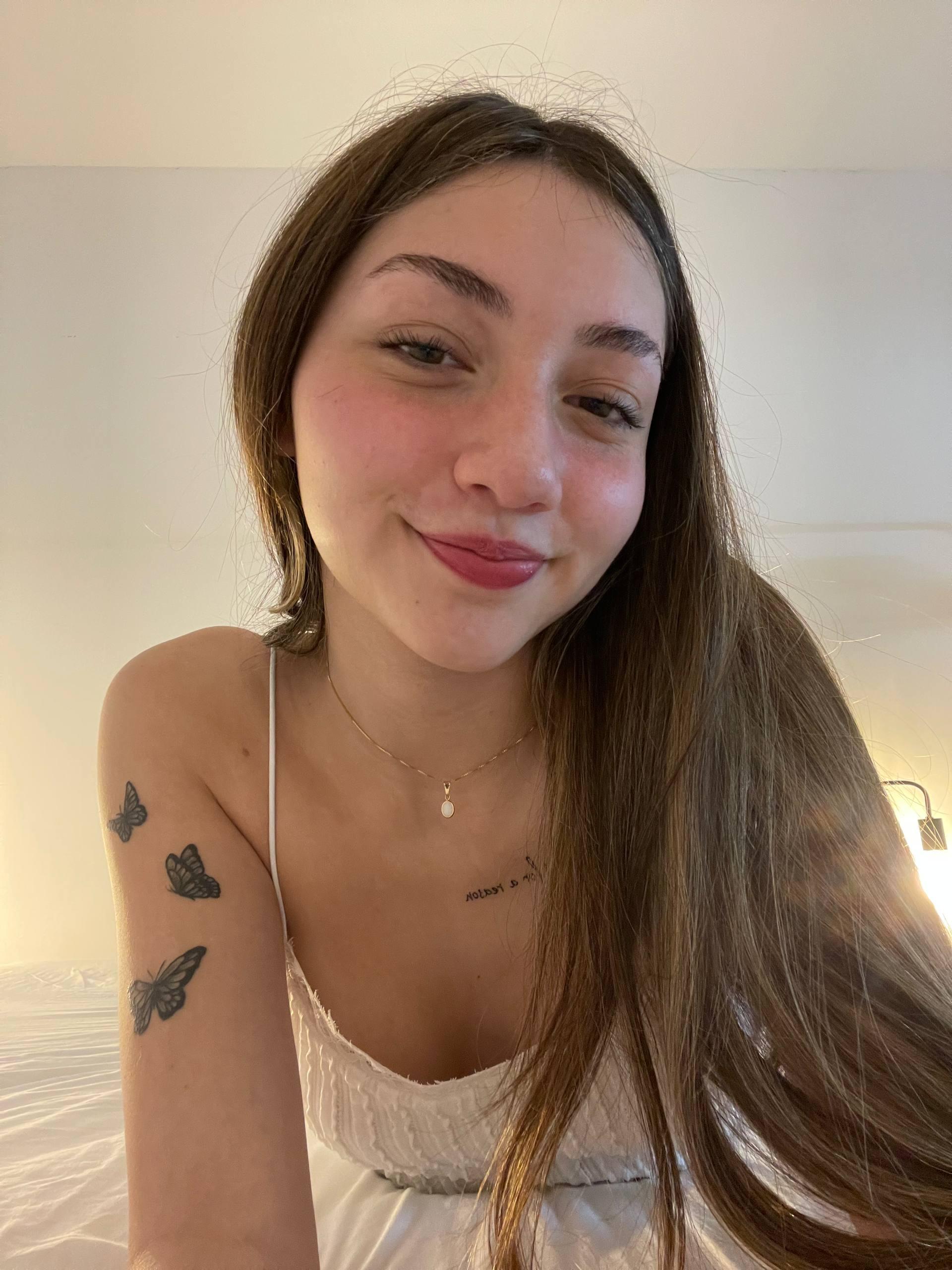 Kiera Brooks's long hair cascades as she winks, her butterfly tattoos and pink lips teasingly inviting.