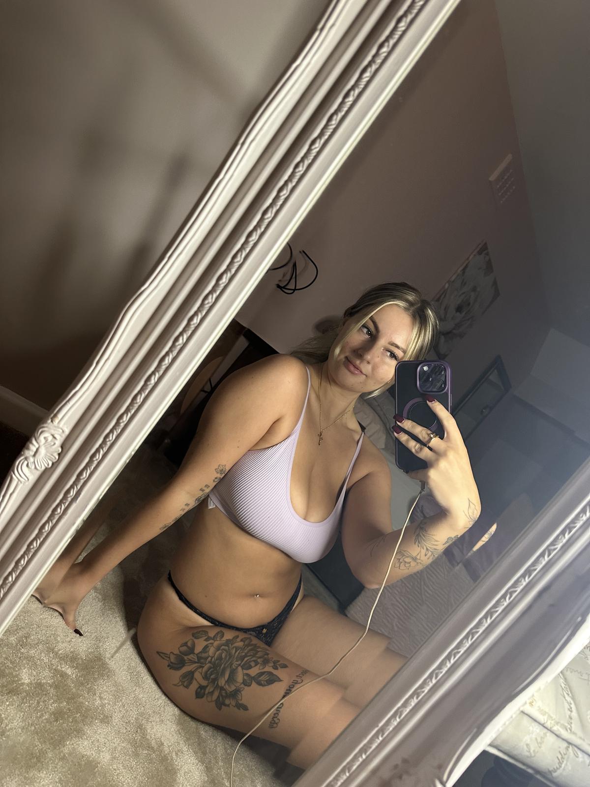 Sofia Bae's tattooed thigh throbs with anticipation as she kneels, her phone capturing her sultry mirror selfie.