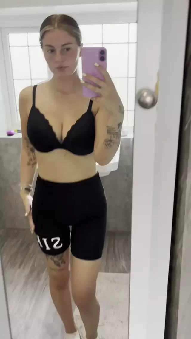 Sofia Bae's hand on her shorts, her black lace bra teasing her full, round breasts, her tattoos on display.