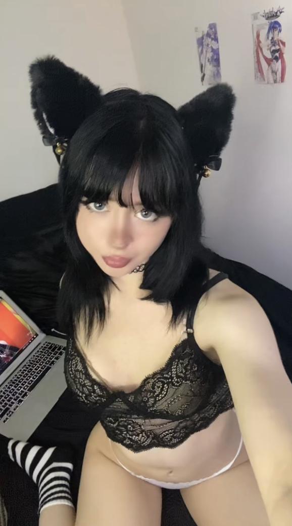 Mimi's black lace bra teasing her small breasts, her eyes locked on you, feeling your gaze intensely.