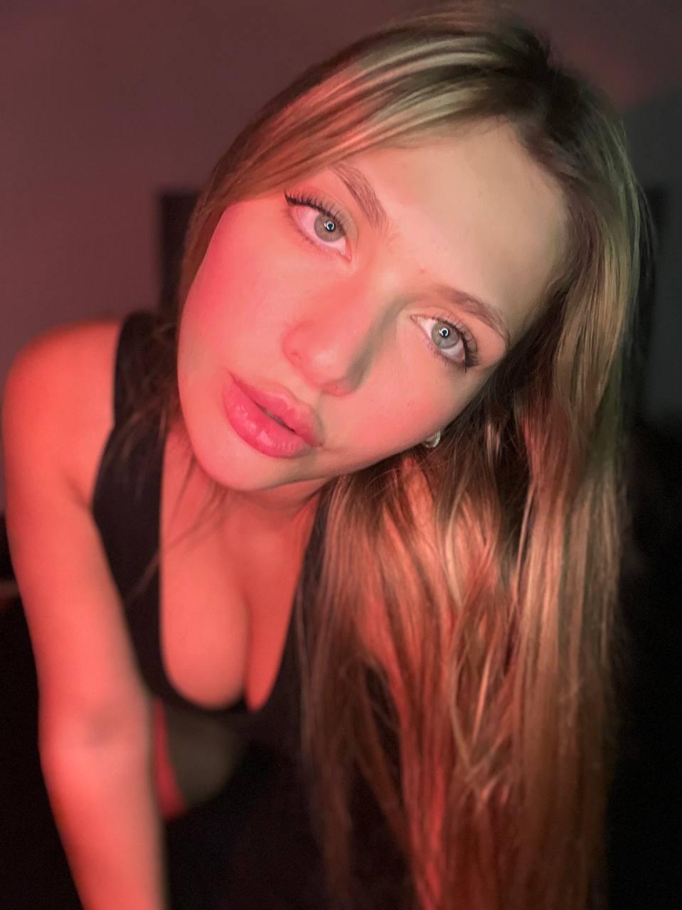 Grace Whitely's lips are slightly parted, her gaze is seductive, and her cleavage is prominently displayed.
