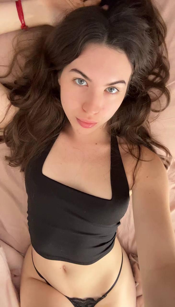 Amber James's wet lips part slightly, her blue eyes locked on you, wearing a black thong, feeling your gaze.