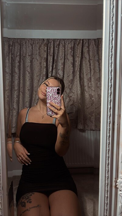 Sofia Bae's tight black dress hugs her curves, her hand on her thigh, anticipating your touch.