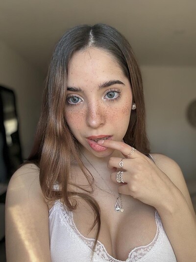 Ella's finger teasing her lips, her blue eyes gazing seductively, her cleavage inviting, her freckles glowing.