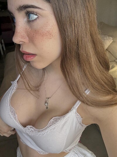 Ella's freckled face is flushed, her blue eyes locked on the camera, her white lace bra teasing her cleavage.