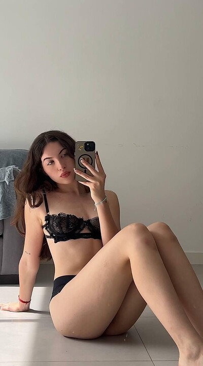 Amber James, sitting, wearing black lace bra and panties, taking a sexy mirror selfie, her legs spread, wet lips.